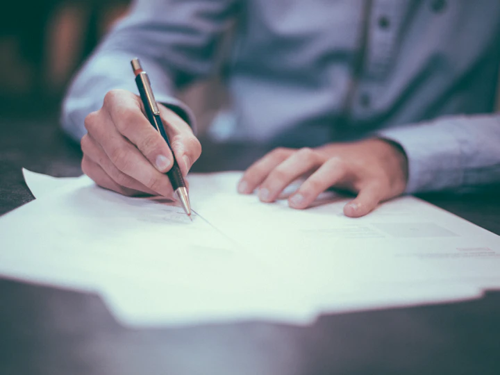 Person signing a document on a desk